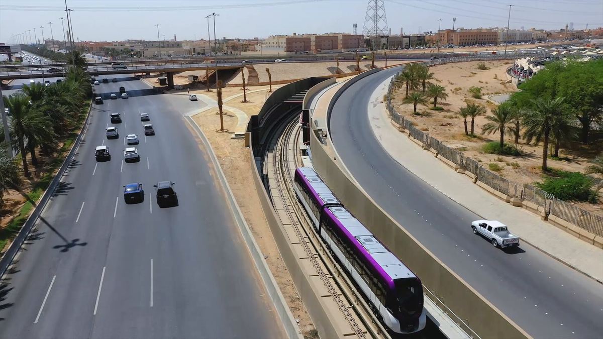 Line 6 train running alongside a busy road