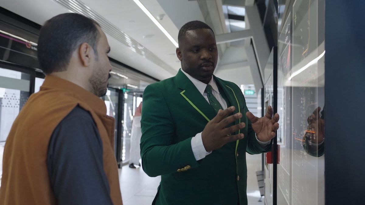 Staff member in green uniform speaking with a passenger