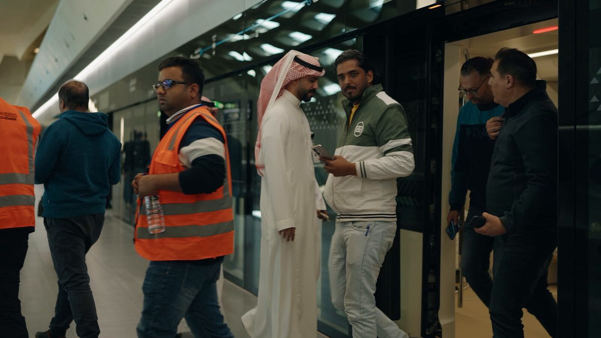 Staff in high-visibility vests with passengers on a platform