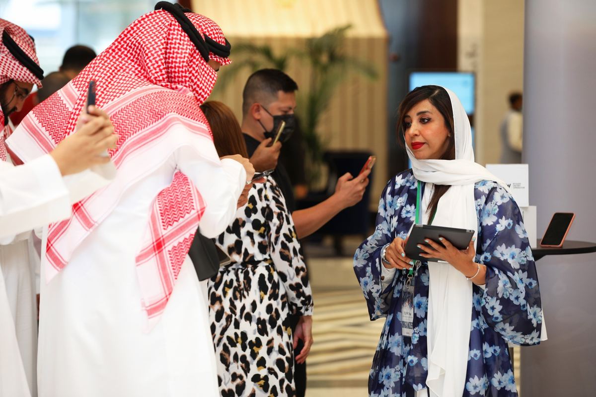 منظِّمة تحمل جهازاً لوحياً بين الضيوف في أحد لقاءات فلو